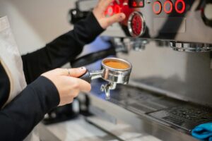A barista prepares coffee using an espresso machine in a cozy café setting.